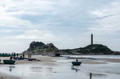 People on sea shore against sky