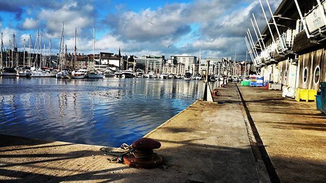 water, nautical vessel, sky, moored, building exterior, transportation, built structure, mode of transport, cloud - sky, boat, architecture, harbor, cloud, pier, sea, city, cloudy, blue, outdoors, day