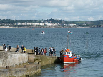 People on boats in sea against sky