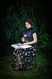 Young attractive woman sitting in a garden with a big book