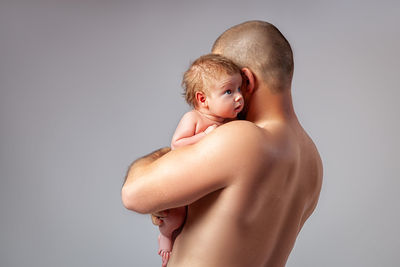 Rear view of shirtless boy against white background