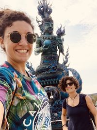 Portrait of smiling woman against statue and sky