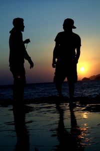 Silhouette man standing on beach against sky during sunset