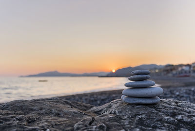 Stack of stones on shore during sunset