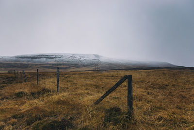 Wooden fence on field against sky