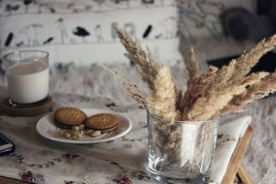 Close-up of breakfast by dry plant in glass on table