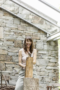 Screaming woman chopping wood in front of a house