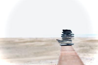 Close-up of chess stack on beach against clear sky