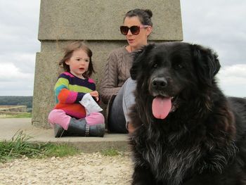 Family with dog sitting against built structure