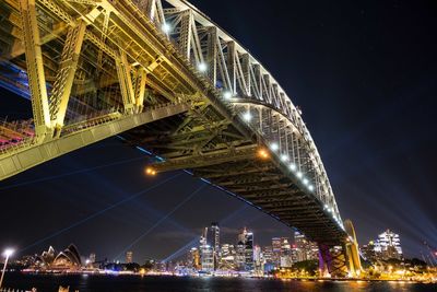Sydney harbour bridge leading to the cbd of sydney at night. lights are emanating from the city