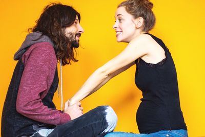 Side view of young couple against yellow background