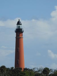 Low angle view of lighthouse by building against sky