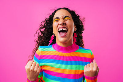 Portrait of young woman standing against yellow background