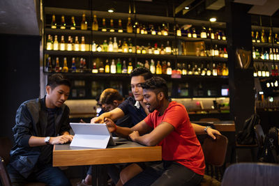 Friends using laptop while sitting in restaurant