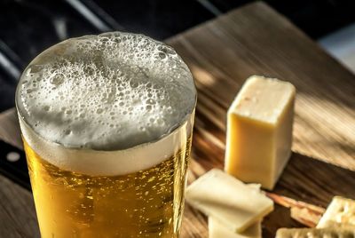 Close-up of frothy beer served on table