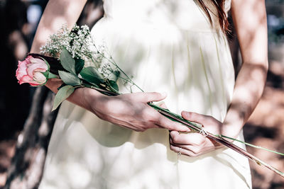 Midsection of bride holding rose