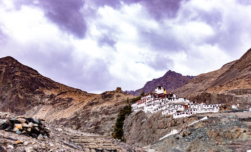 Low angle view of houses on mountain against cloudy sky