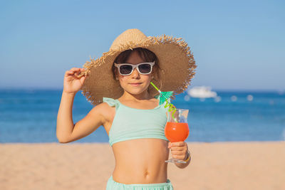 Portrait of woman wearing sunglasses while standing at beach