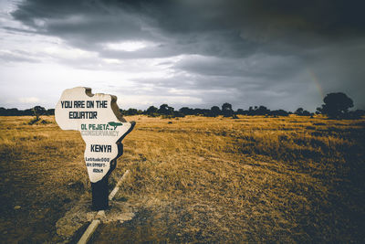 Information sign on field against sky