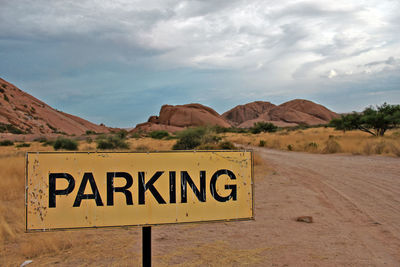 Road sign against cloudy sky