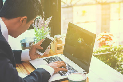 Midsection of man using mobile phone at table