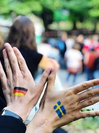 Cropped image of person with painted flags on hand