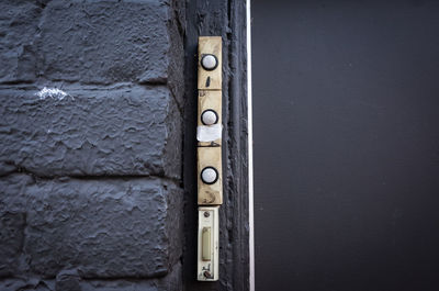 A column of 4 old doorbells next to a door.