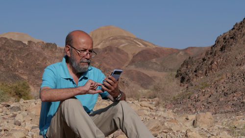 Senior man using smart phone in the desert 