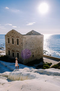 Woman standing on beach by sea against sky