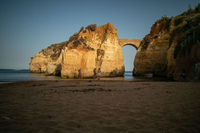 Rock formations on beach against clear sky