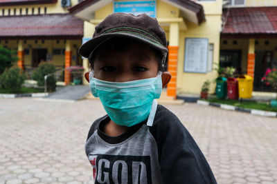 Portrait of boy wearing pollution mask while standing on road