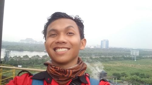 Portrait of smiling young man with cityscape in background