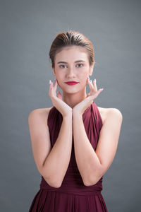 Portrait of young woman against gray background