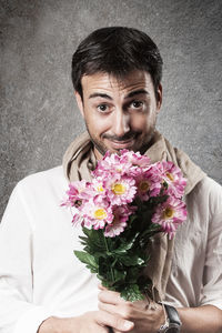 Portrait of young man holding pink flower