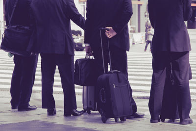 Low section of business people with luggage on road