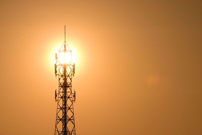 Low angle view of silhouette electricity pylon against sky during sunset