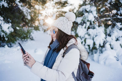 Midsection of woman holding smart phone during winter