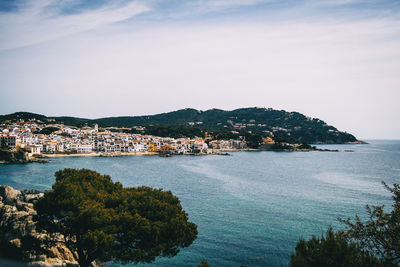 Scenic view of sea by townscape against sky