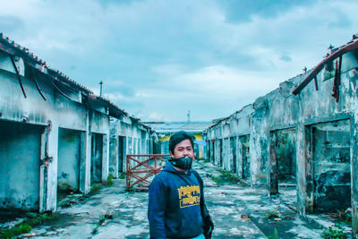 Portrait of young woman standing against abandoned building