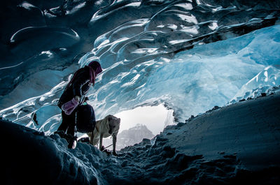 Full length of woman standing with dog in ice cave