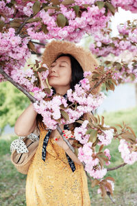 Young japanese woman wearing hat among cherry trees