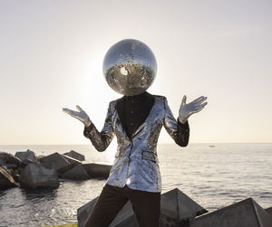 Rear view of person standing on rock by sea against clear sky