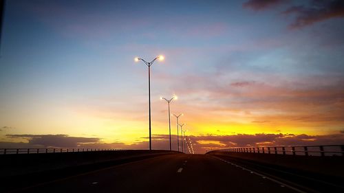 Street lights against sky during sunset