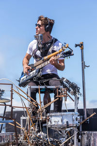 Man playing guitar against clear sky