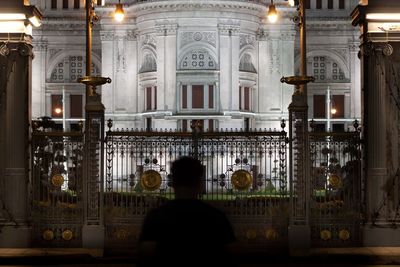 Rear view of man against illuminated building