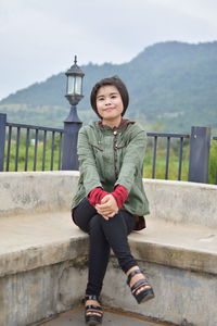 Portrait of woman standing against railing