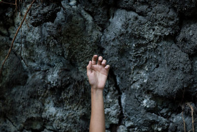 Cropped hand against rocks