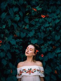 Young woman looking away against plants