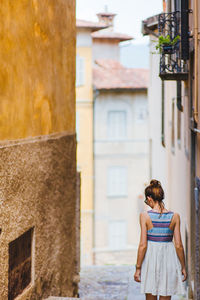 Rear view of woman standing against building