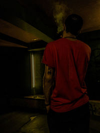 Rear view of man standing in illuminated building